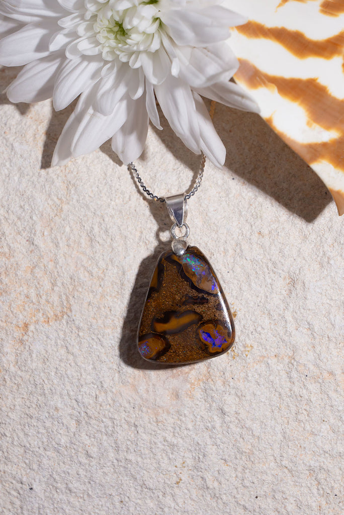 An Australian opal pendant with all the colours of the outback and three bright ponds of mauve and green rising through the stone.