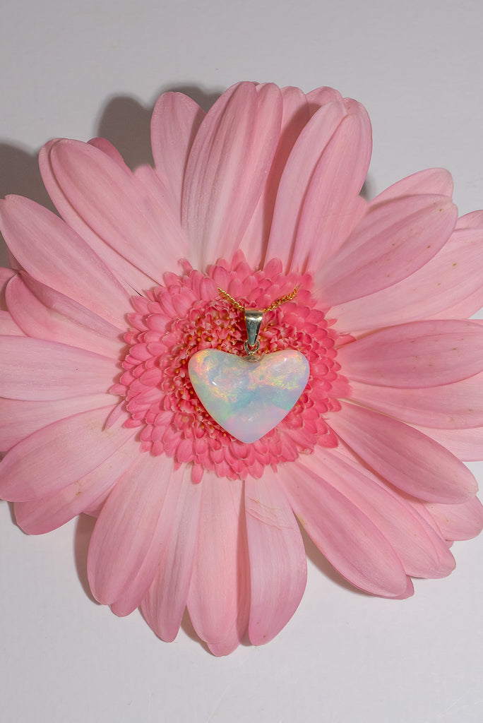 A lovely bright pastel coloured crystal opal heart pendant, very crystalline with tones of pink, apple green, and soft teal. The heart is rippled like the surface of a mystical land.