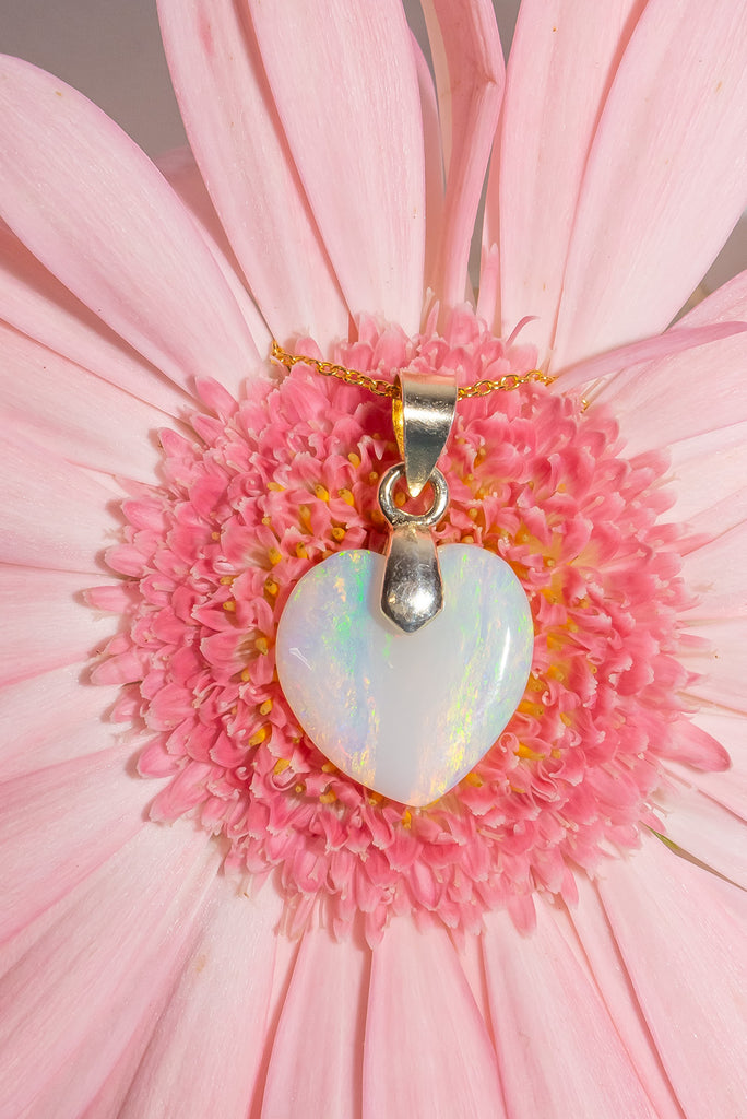 This is a really lovely opal heart pendant the crystal has shimmer in pink, green, and gold, the shape is very pure and harmonious. Romance in a stone.