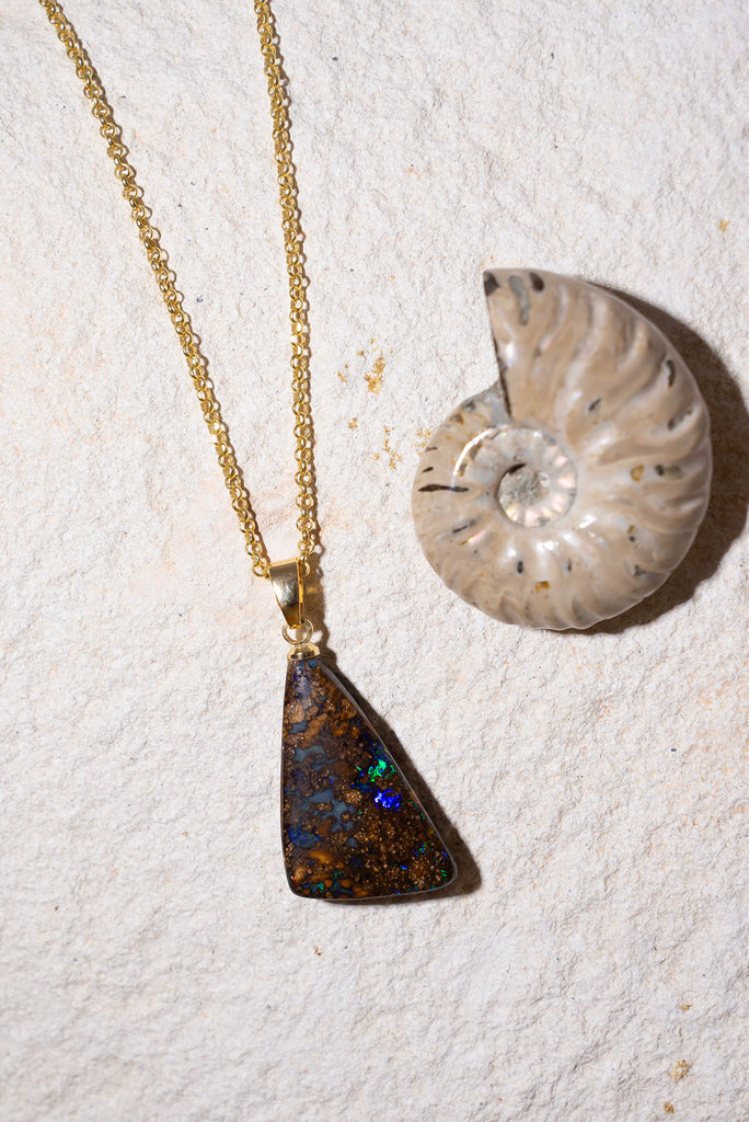 Discover a rainbow sparkle amongst the beautiful polished boulder stone of this pendant.