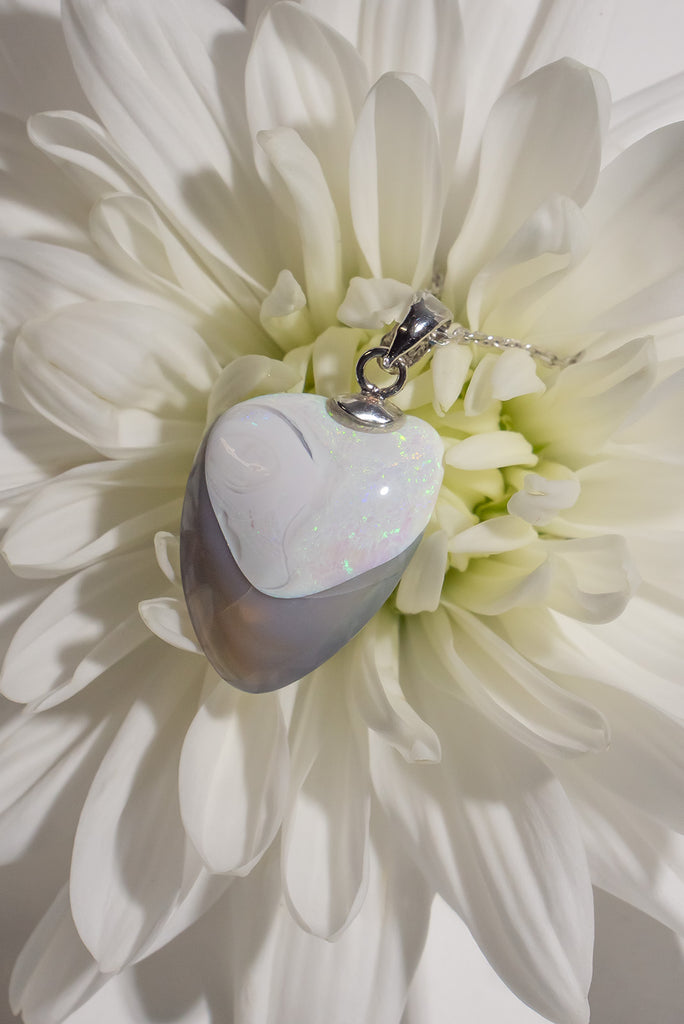 A totally unique opal pendant, when examining the stone our cutter found a perfect heart with a perfect shadow of crystal opal. The white at the top is sprinkled with tiny pink and green sparkle, this opal has a mystery all of its own.