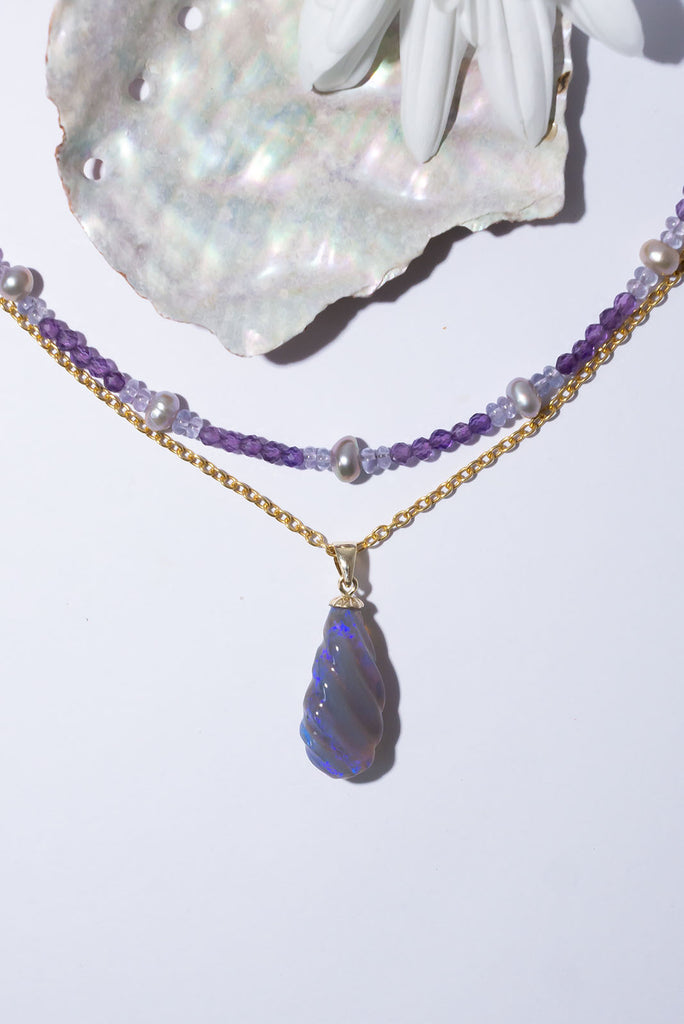 This gorgeous twist of Lightning Ridge Opal shimmers with enchanting flecks of dark blue & purple fire.