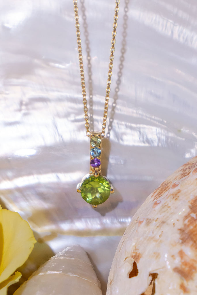 A pretty sparkling pendant featuring a round faceted Peridot gemstone set in 9ct gold vermeil, the accent is a bar of tiny amethyst, peridot and blue topaz accent stones.