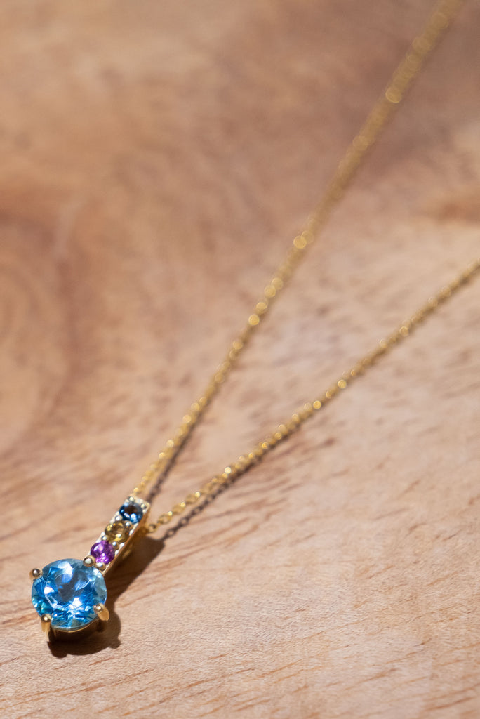 A pretty sparkling pendant featuring a round faceted Swiss Blue Topaz gemstone set in 9ct gold vermeil, the accent is a bar of tiny amethyst, citrine and blue topaz accent stones. 