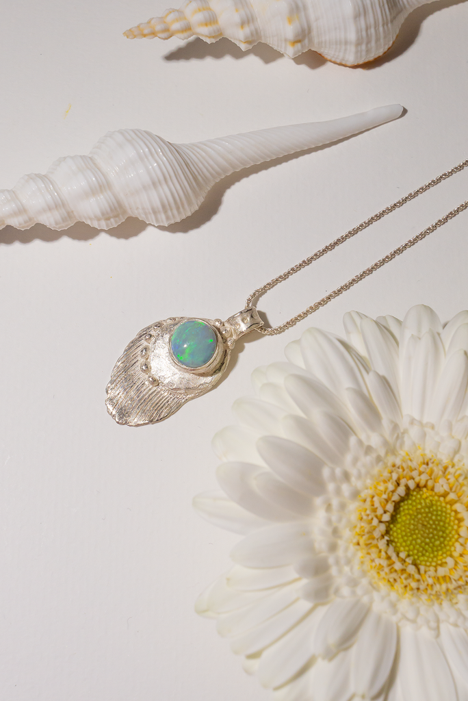 The pendant is solid silver, it is cast from a shard of old sea worn shell and has a beautiful Australian opal set onto the front. This pendant is handmade and totally unique