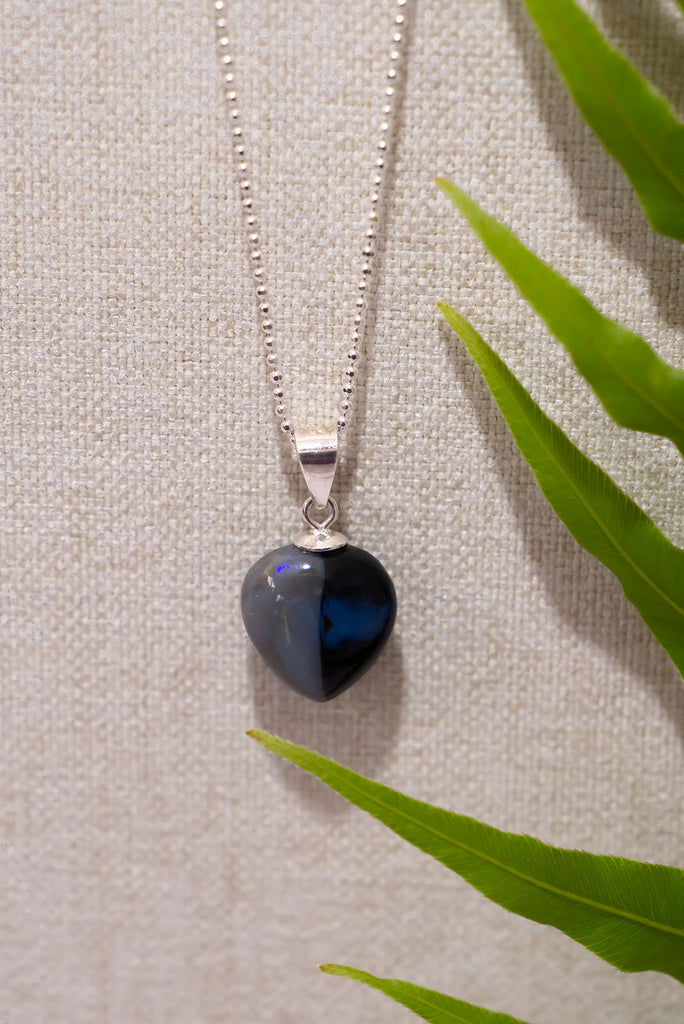 This unique black opal is divided by a tiny crystal window straight down the centre, one side is silvery grey the other black with a soft blue pool of colour. Its full of intrigue.