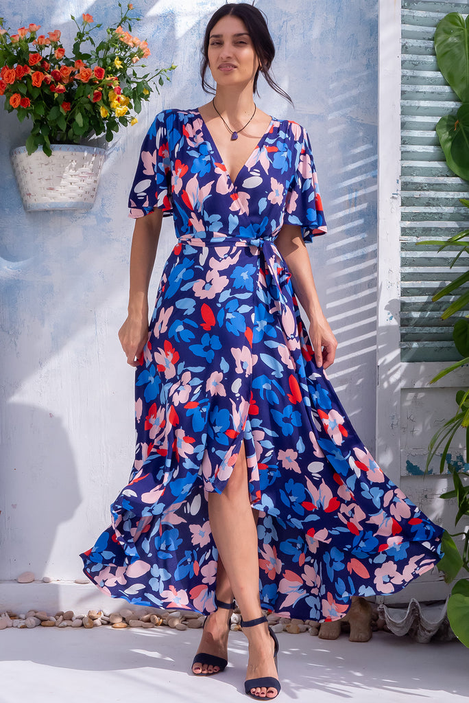 The Petal Blue Charm Maxi Wrap Dress is a beautiful blue maxi wrap dress with a large floral print. The dress features flutter sleeves, a functional wrap design, and side pockets. Made from 100% rayon.