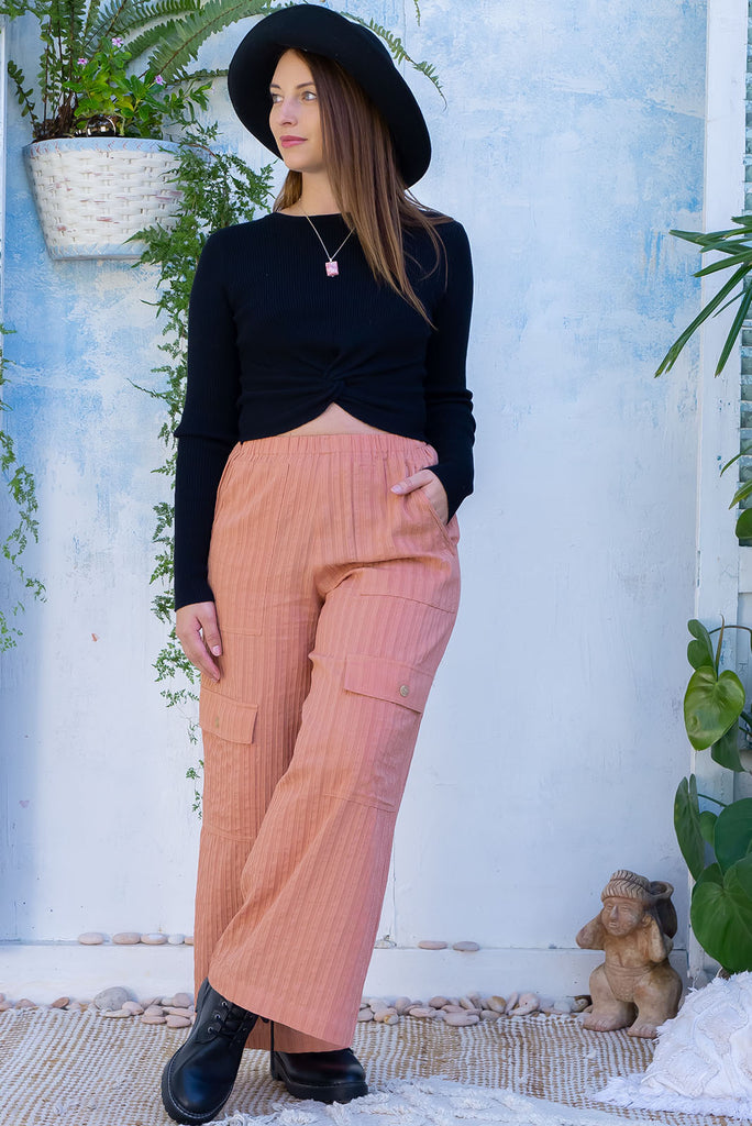 The Traveller Desert Pants are a gorgeous peachy orange pair of mid-rise cargo style pants. The pants feature an elasticated waist, side pockets, wide legs, and patch pockets. Made from 100% cotton.