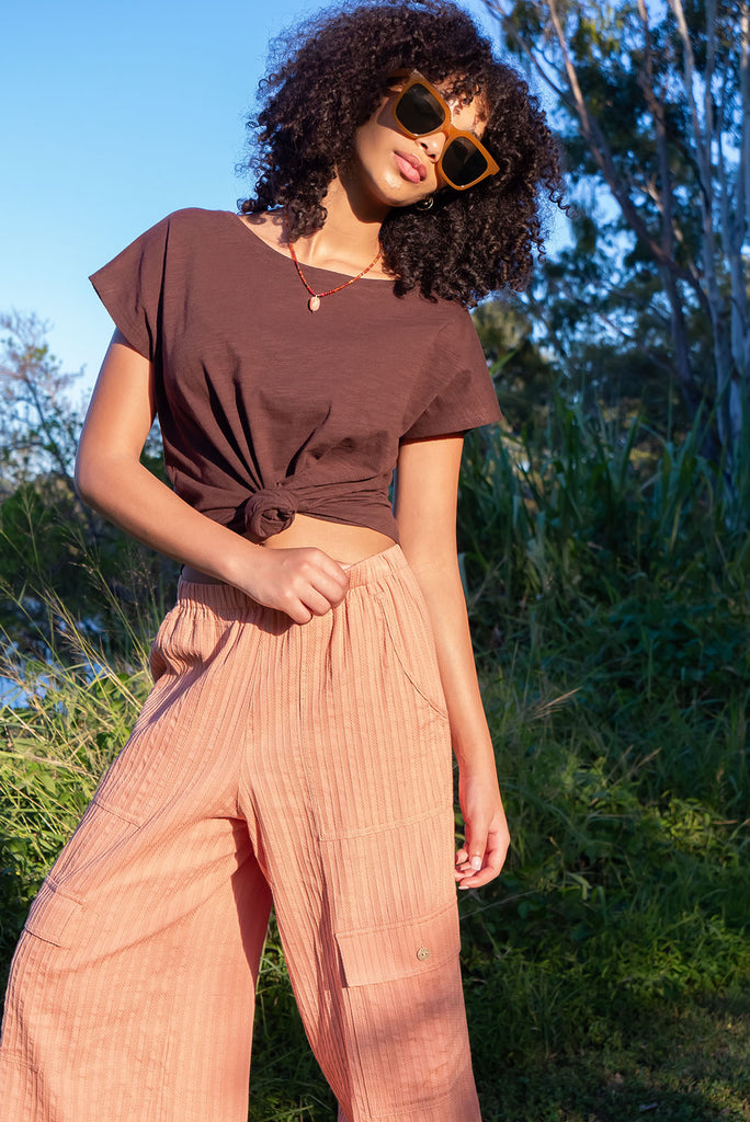 The Traveller Desert Pants are a gorgeous peachy orange pair of mid-rise cargo style pants. The pants feature an elasticated waist, side pockets, wide legs, and patch pockets. Made from 100% cotton.
