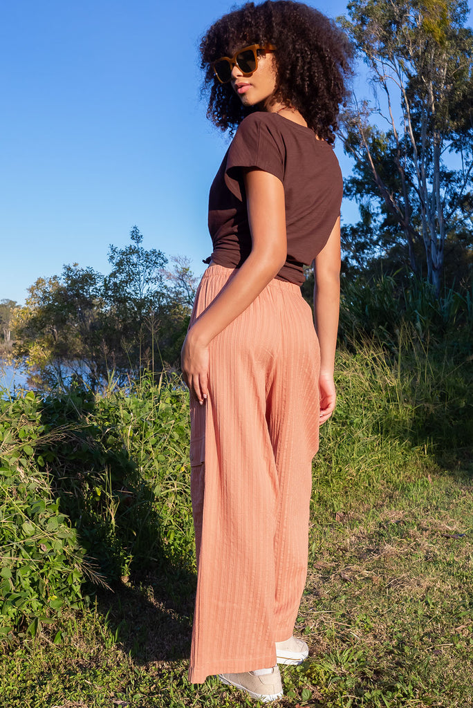 The Traveller Desert Pants are a gorgeous peachy orange pair of mid-rise cargo style pants. The pants feature an elasticated waist, side pockets, wide legs, and patch pockets. Made from 100% cotton.