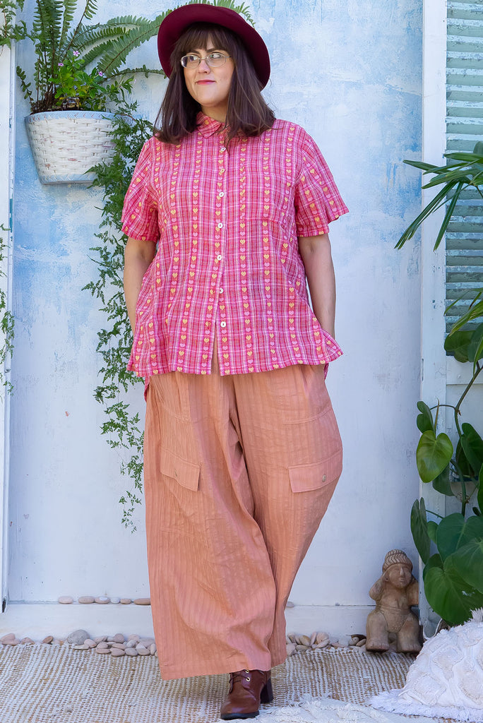 The Traveller Desert Pants are a gorgeous peachy orange pair of mid-rise cargo style pants. The pants feature an elasticated waist, side pockets, wide legs, and patch pockets. Made from 100% cotton.