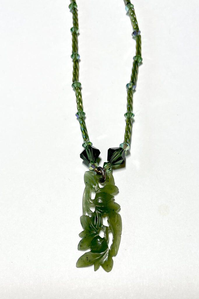 necklace is opera length and can be worn long or doubled to be shorter. Crystal glass bugle beads and green Swarovski crystals. The centre is a pendant of beautifully carved foliage in greenstone jade.