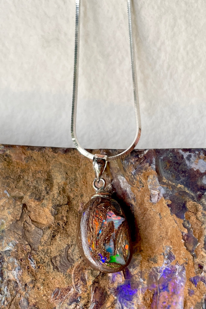 This opal has a lovely flashes of colour across the centre of the stone, predominately red and pink but with green and yellow as well. It is cut into a rounded oval and shows the mark of the artist who cut and polished the stone. This genuine Australian Boulder Opal stone was cut and polished in Queensland by an Opal miner.
