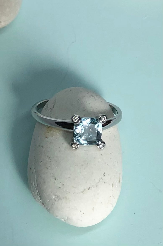 This ring gives a modern twist to antique styling. The lovely square cushion cut and faceted Aquamarine is off set by four one point diamonds