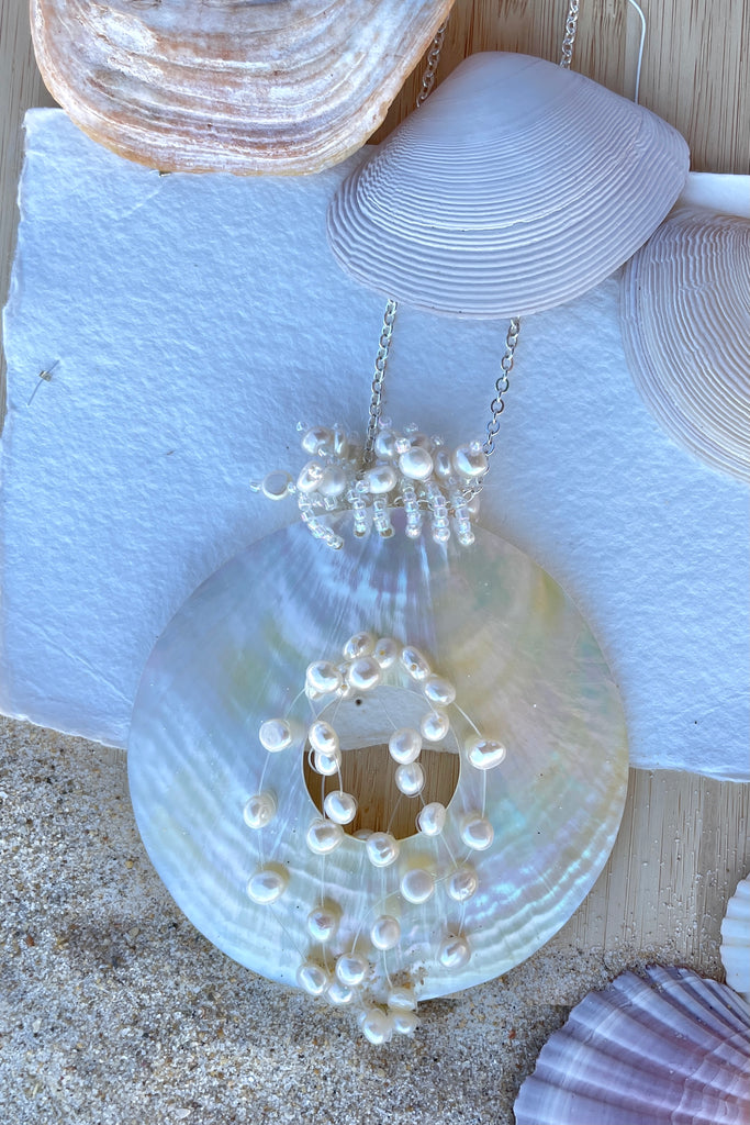 An iridescent circle of beautiful golden Mother of Pearl shell, hung with pearls on a simple silvery chain.