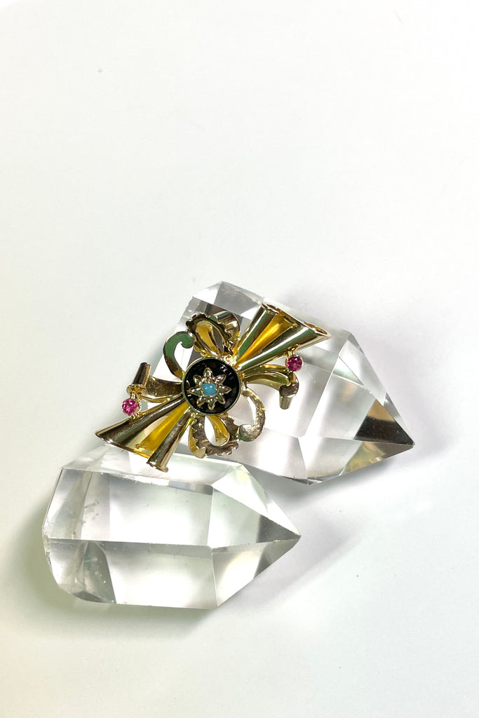 the brooch is unmarked gold with two tiny pink stones either pink garnet or ruby, the centre is black onyx with a star that has a turquoise centre stone.