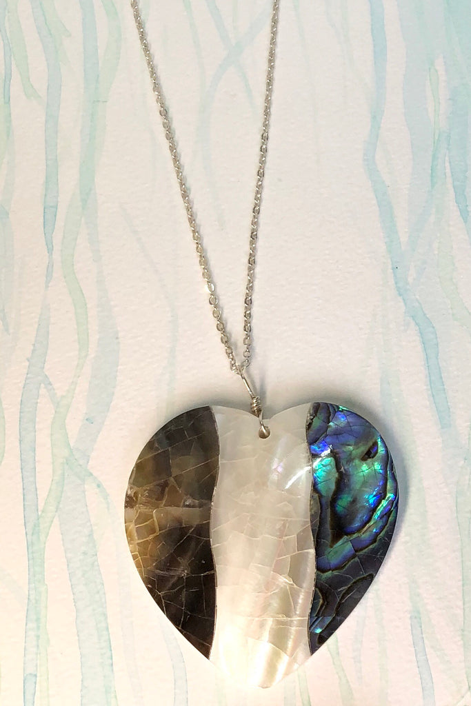 A charming heart shaped pendant, the surface is silvery grey blue and pearly white mother of pearl shell that has been applied to a base of shell, so it is lovey worn both ways around.