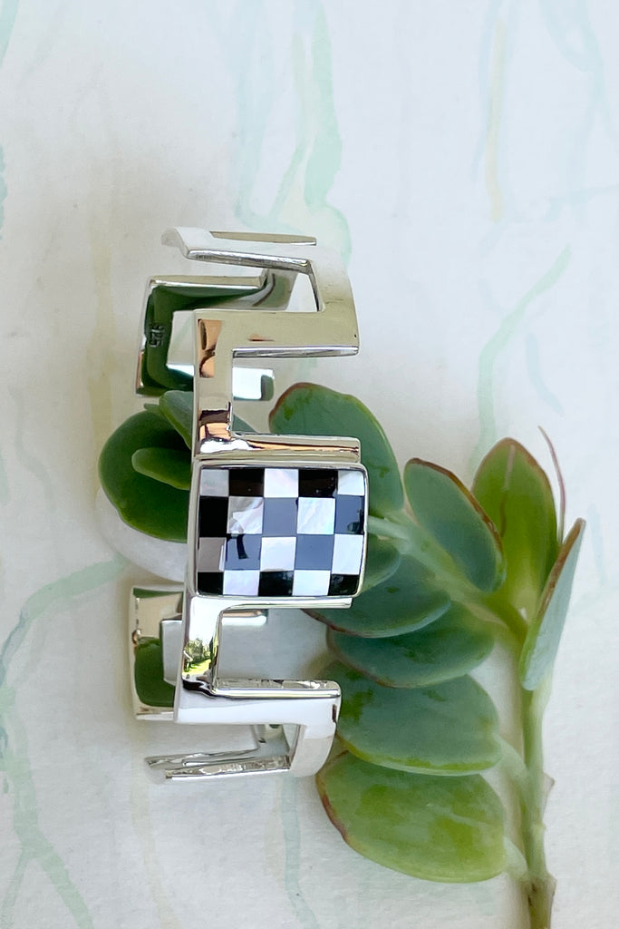 Very cool and sophisticated, this 925 silver cuff bracelet rocks the modern retro cool. In a square geometric design featuring a centre square inlaid with mother of pearl and black enamel,