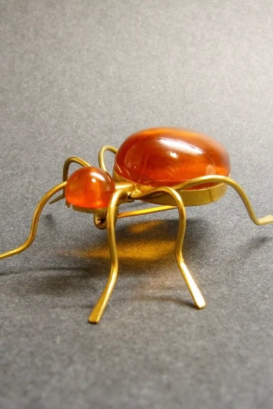 Features the form of a six legged bug with the head and body set with cabochons of natural Baltic honey amber. Marked on underside. A super quirky insect brooch