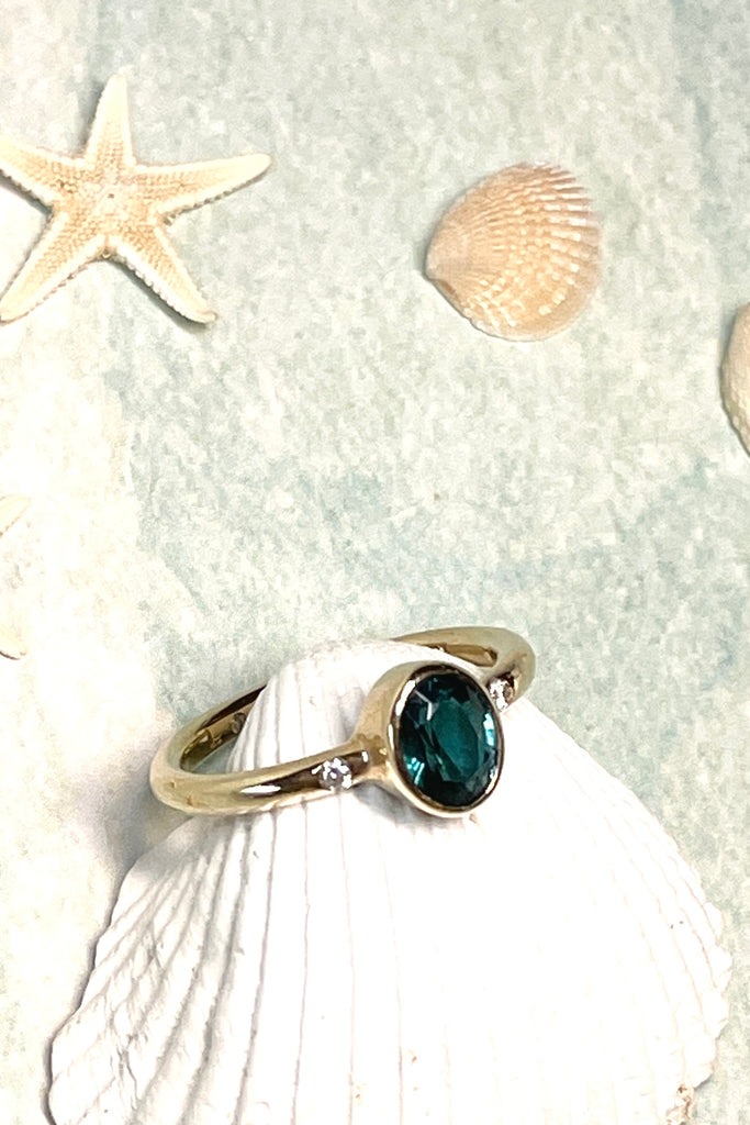 A beautiful simple ring designed to complement the lovely natural teal blue tourmaline gemstone set into the ring. The shank of the ring has a diamond on each side of the centre stone.