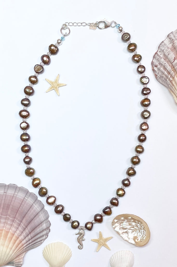 pearl necklace Cay Precious has golden cognac pearls interspaced with Swarovski crystals. There is a tiny silver seahorse as a centerpiece.