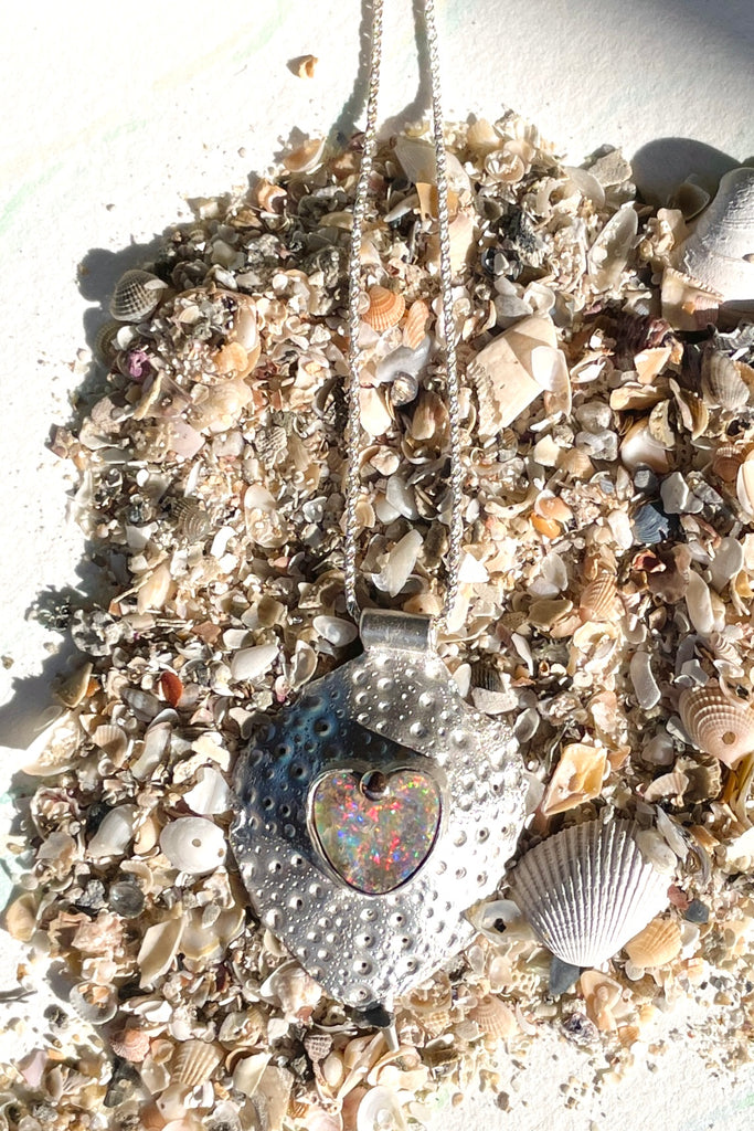 The heart opal centre piece is cut from natural solid Australian Opal. The silver is moulded from the shell of a sea urchin, then the opal is applied with the aid of a small gold dot of repurposed 18ctgold.
