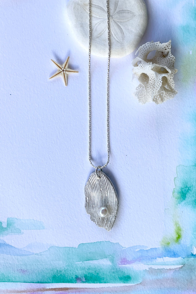 The pendant is solid silver, it is cast from the surface of a Pippi shell, and designed to carry the pearl bubble on the waves reaching the shore.
