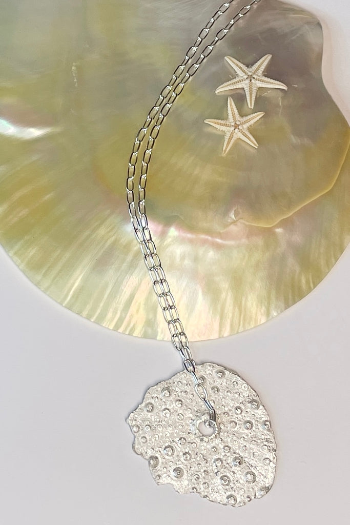 . The centre piece is silver, it is cast from a sea urchin shell. This pendant  is so delicate and has the feeling of a tiny sparkly shard floating in the ocean. 