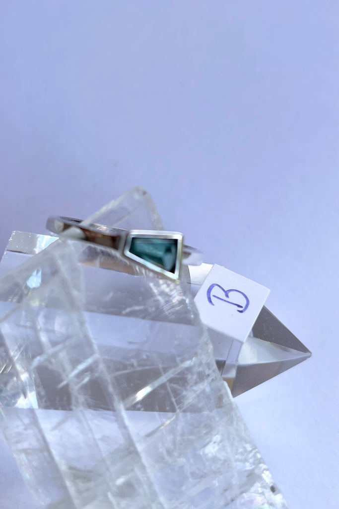 This pale blue green natural tourmaline has been cut in an elegant free form geometric style, then set to fit its unique lines and brilliant colours creating a one of a kind piece. 