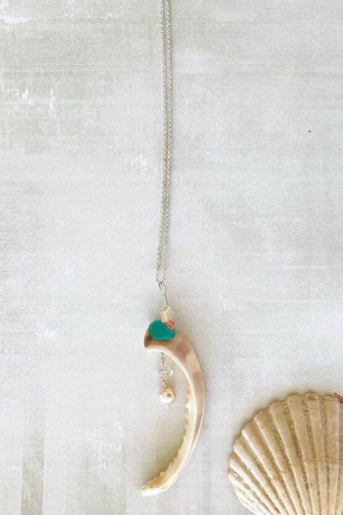 A beautiful cowrie shell lip as found on the beach, this has been turned into a pendant featuring a lustrous natural pearl, a Herkimer diamond an Amazonite bead and a mother of pearl star.