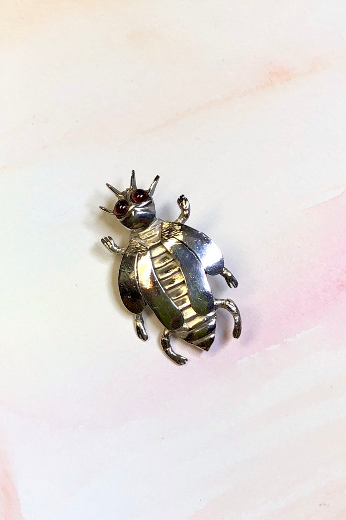 A vintage silver beetle brooch with garnet gemstone eyes.