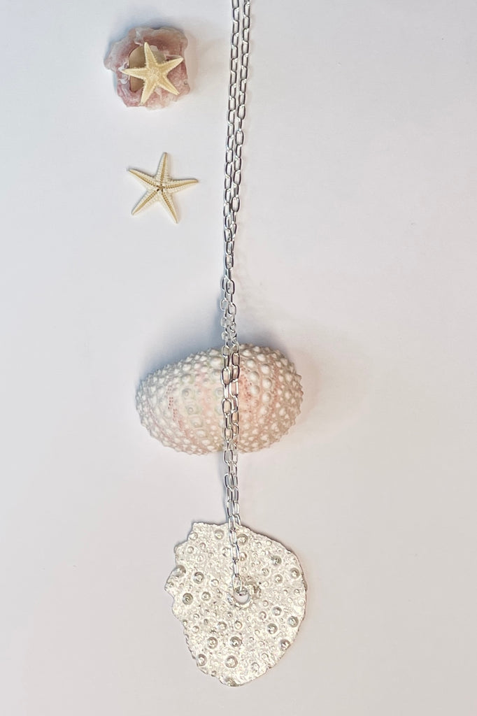 . The centre piece is silver, it is cast from a sea urchin shell. This pendant  is so delicate and has the feeling of a tiny sparkly shard floating in the ocean. 