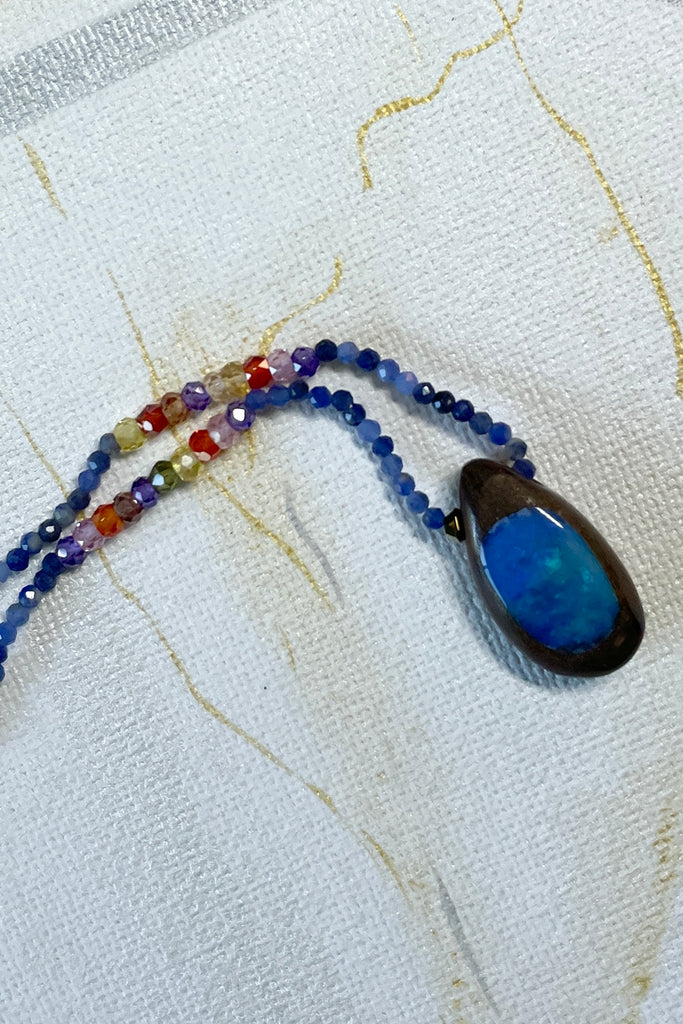This tiny pendant is made by fusing a fine flash slice of Australian crystal opal into natural boulder stone. The necklace is strung with very tiny faceted chalcedony gemstones