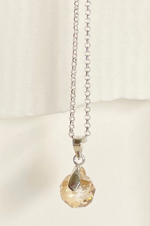 A dainty crystal bead hung from a silvery bail. 