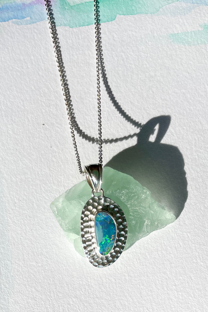 The Australian opal pendant is shaped into an abstract shape with a polished frame