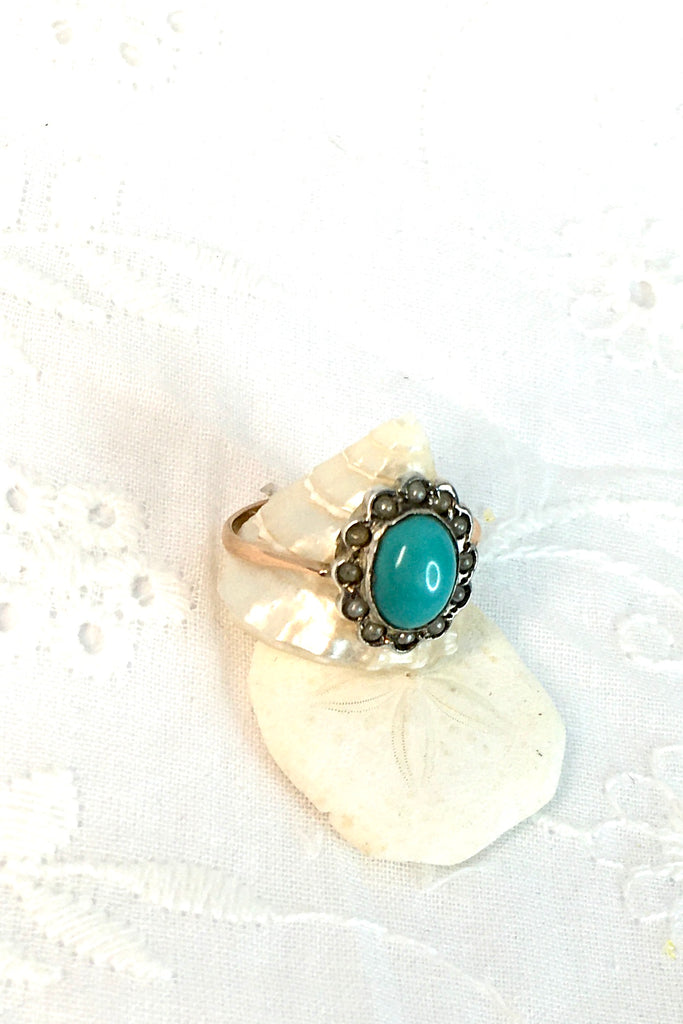 This Vintage with a solid turquoise centre stone has a surround of old 1/2 pearls, this ring has a fine band in 9ct gold. 