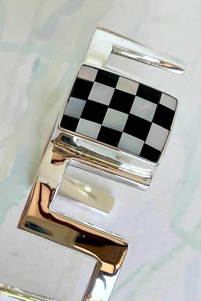 Very cool and sophisticated, this 925 silver cuff bracelet rocks the modern retro cool. In a square geometric design featuring a centre square inlaid with mother of pearl and black enamel,