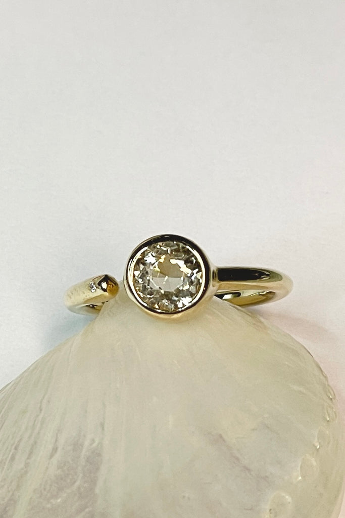 this stunning 10k gold ring is set with a beautiful untreated soft yellow Nigerian Tourmaline offset by a sparkling 1pt Diamond. The setting features a band that ends before the stone, leaving a tiny gap enhanced with a diamond.