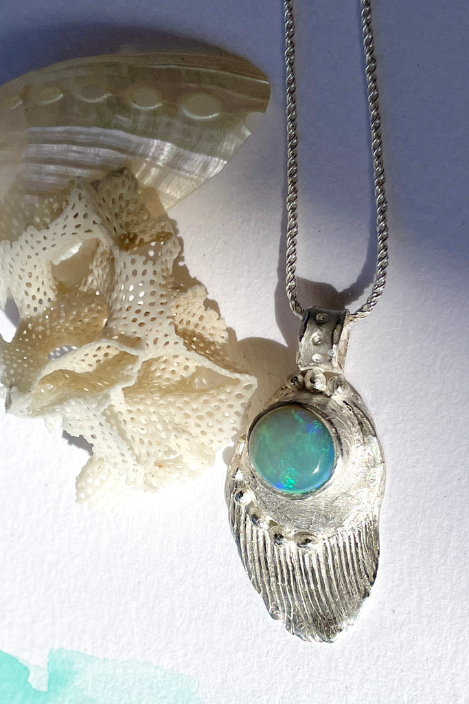 The pendant is solid silver, it is cast from a shard of old sea worn shell and has a beautiful Australian opal set onto the front. This pendant is handmade and totally unique