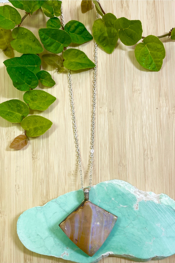 Cut into a rough hewn triangle shape it has rivers of pale turquoise green opal flash on the front. 