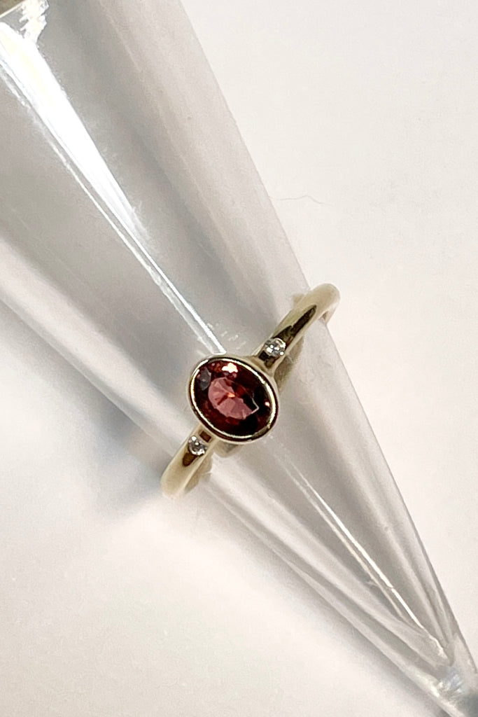 A beautiful simple ring designed to complement the lovely deep peachy red tourmaline gemstone set into the ring. The shank of the ring has a diamond on each side of the centre stone. 