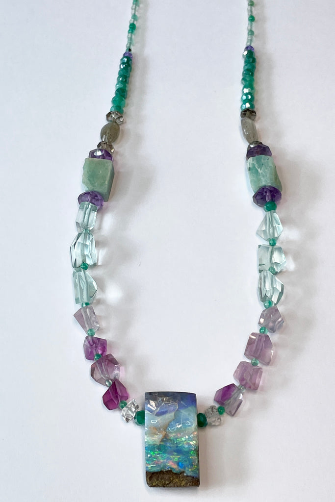Opal necklace  The centrepiece is cut from an opal "split" so the surface is not polished but left exactly as it has been for millions of years. the back and sides are curved and polished to a soft shine. Bright flashes of crystal blue, green and mauve 
