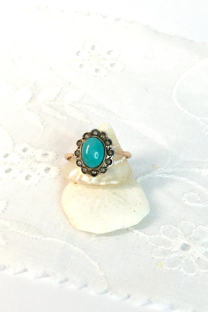 This Vintage with a solid turquoise centre stone has a surround of old 1/2 pearls, this ring has a fine band in 9ct gold. 