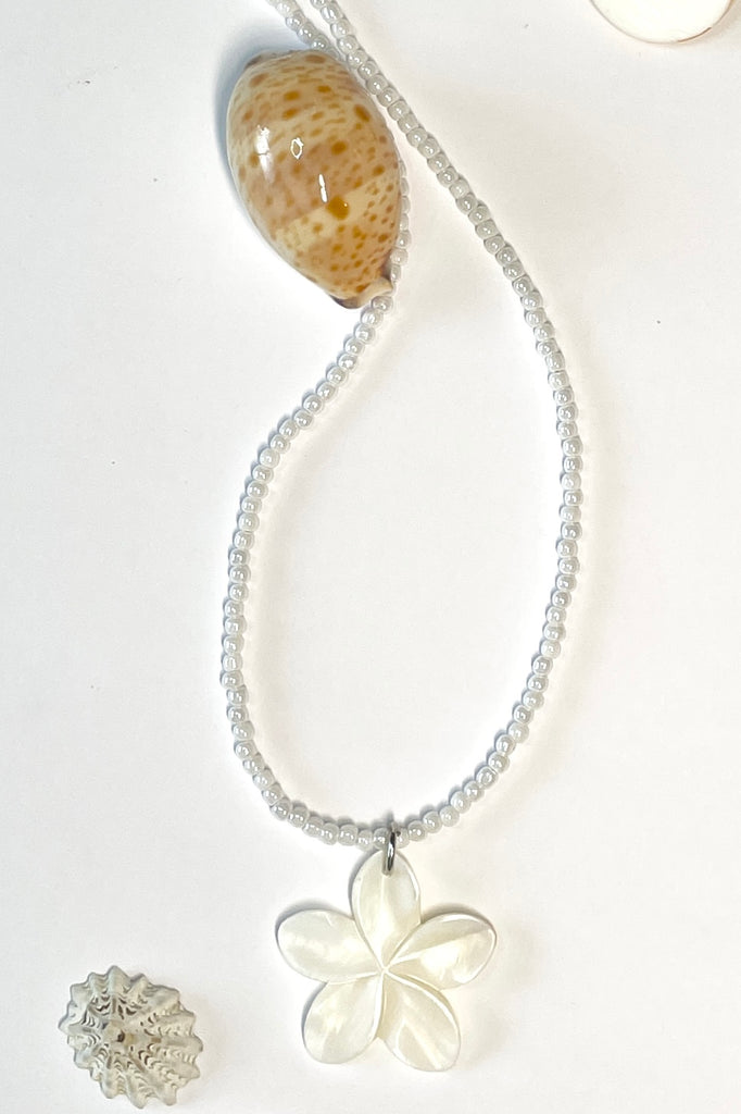 hand carved from Mother of Pearl shell all carry the distinctive marks of the artist who created them, no two flowers are ever alike,  strung on pearlescent white glass beads