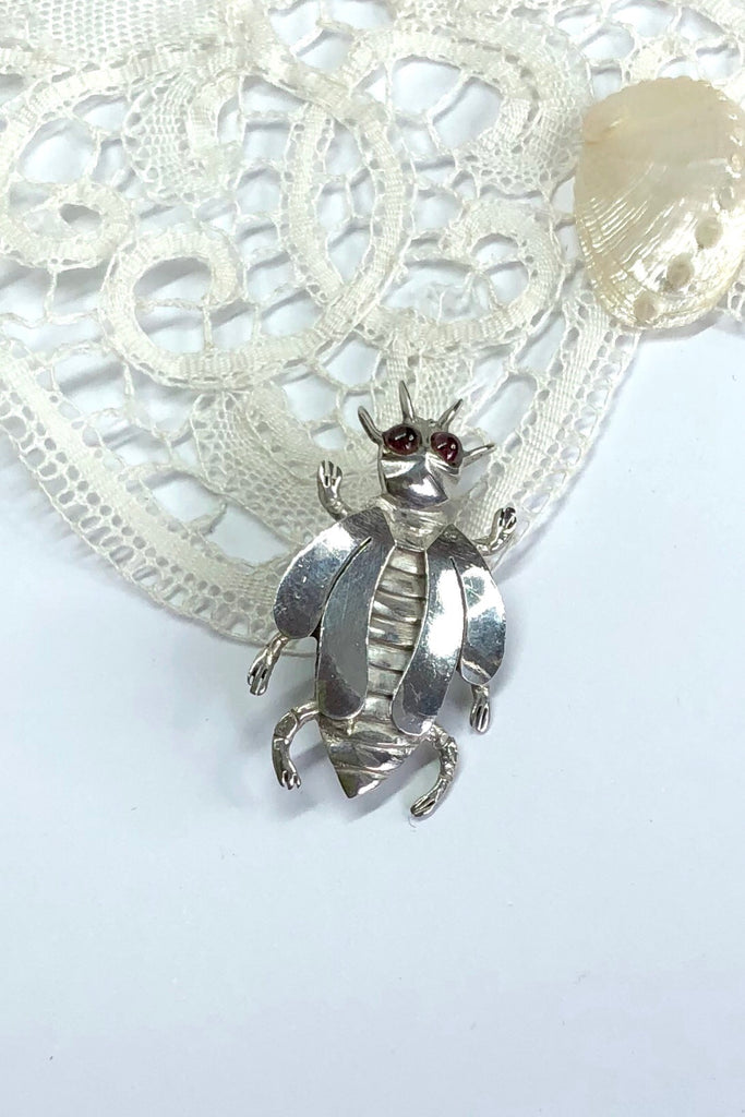 A vintage silver beetle brooch with garnet gemstone eyes.