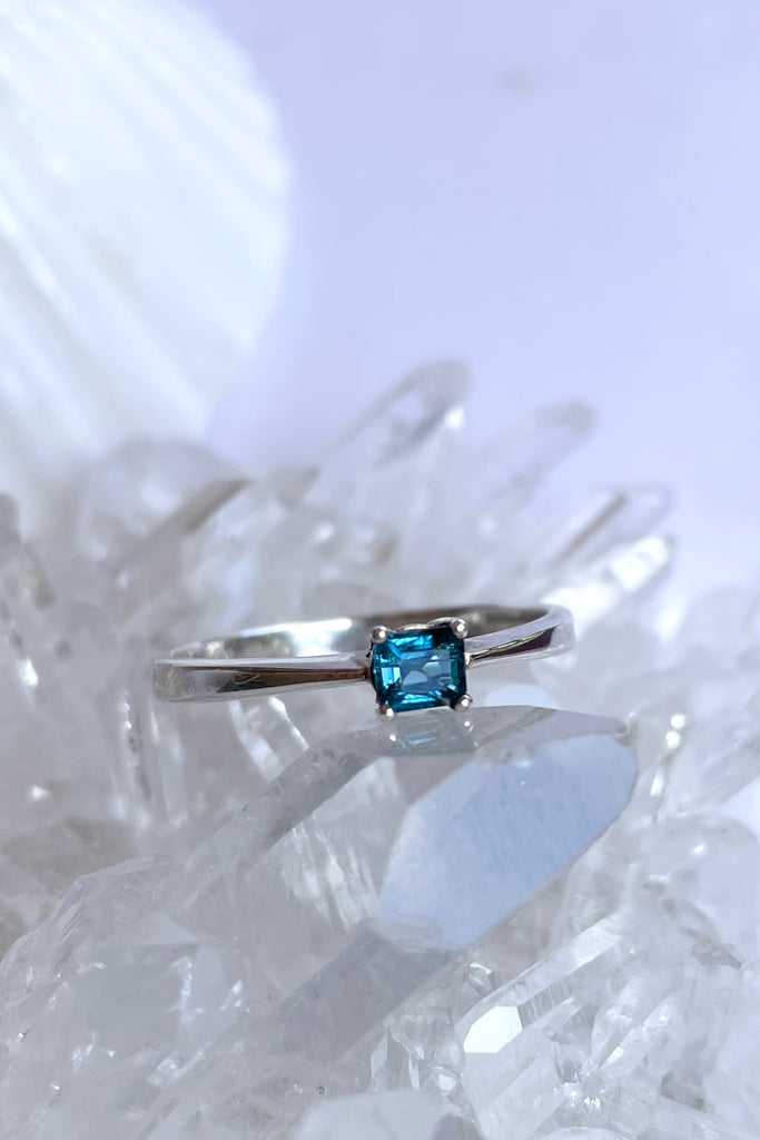 This pretty bright blue natural tourmaline has been cut in a square faceted stone. Set in a slightly raised prong setting.