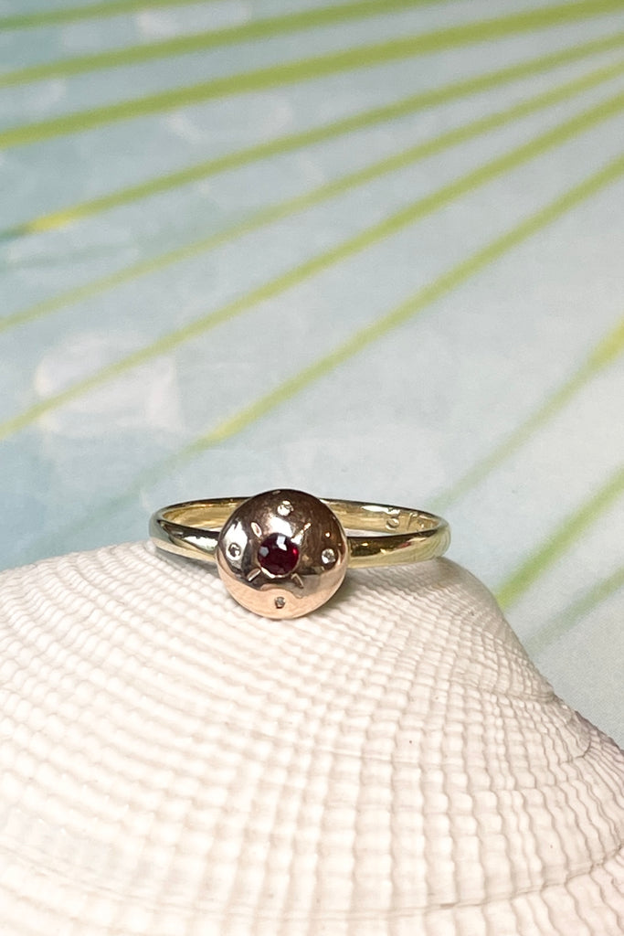 This Vintage diamond ring features a  central dark red garnet and four tiny diamonds. In 9ct gold band, the centre is in rose gold