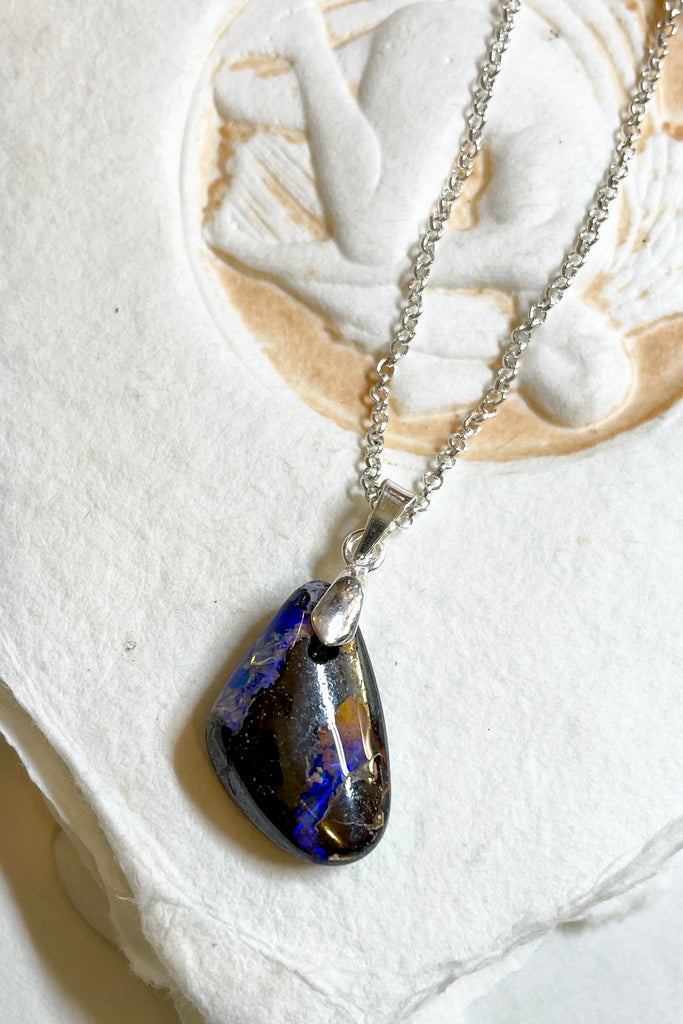 A tiny organic triangular piece with deep flashes of dark blue and crystal through the piece. Perfect entry level Opal.