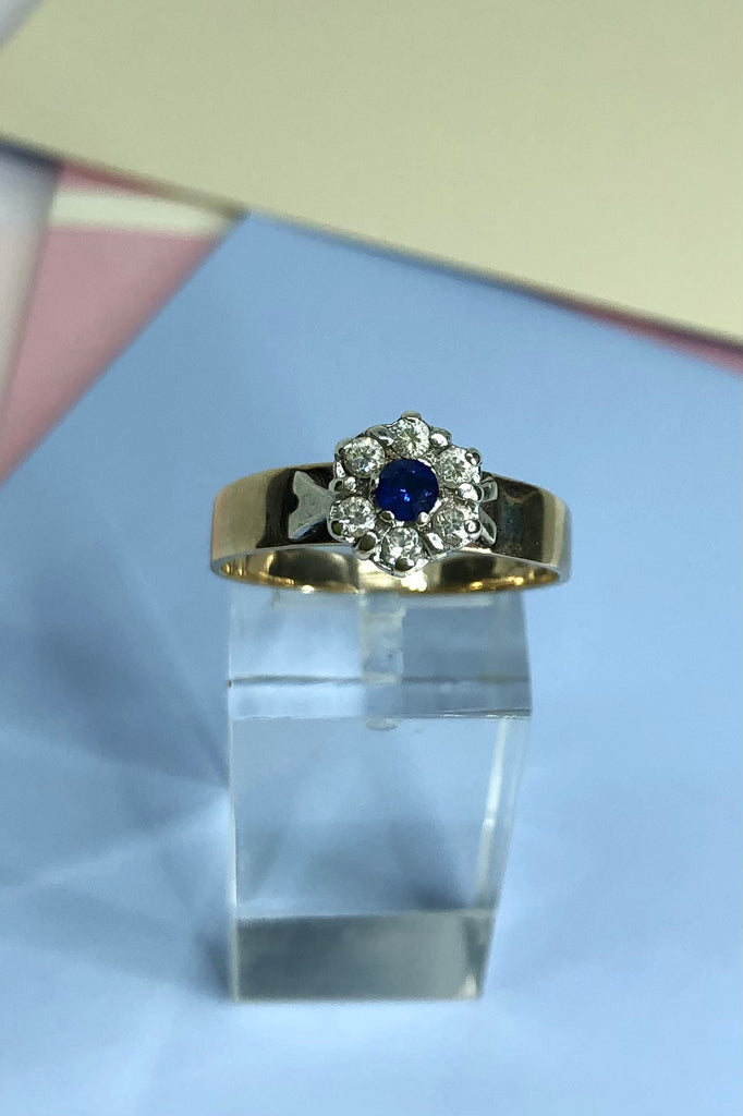 This Vintage ring features a very high setting, a small clear blue sapphire is halo set with six old cut white topaz. 