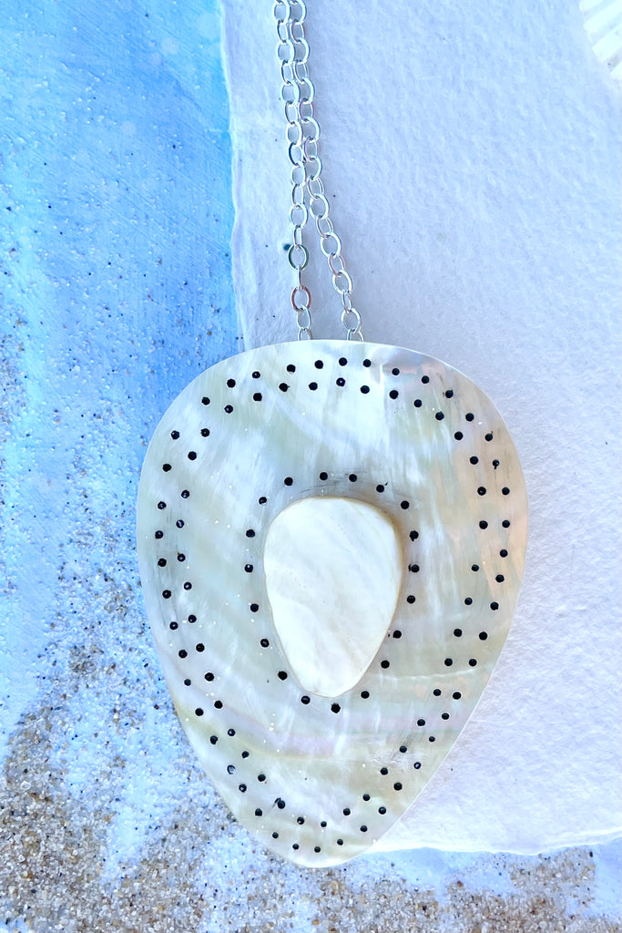 Beautiful golden Mother of Pearl shell pendant cut into a strong tribal shape, it has inlaid spots that give it the feeling of strength